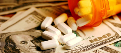 prescription bottle spilling pills onto $100 bills
